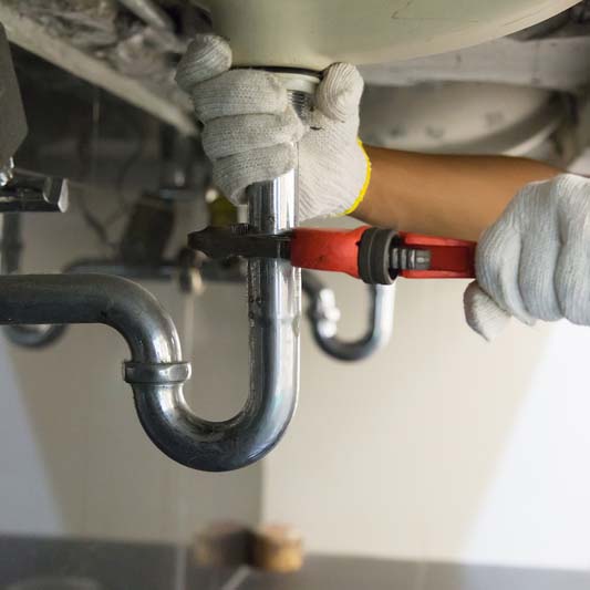 sink being fixed with a red wrench